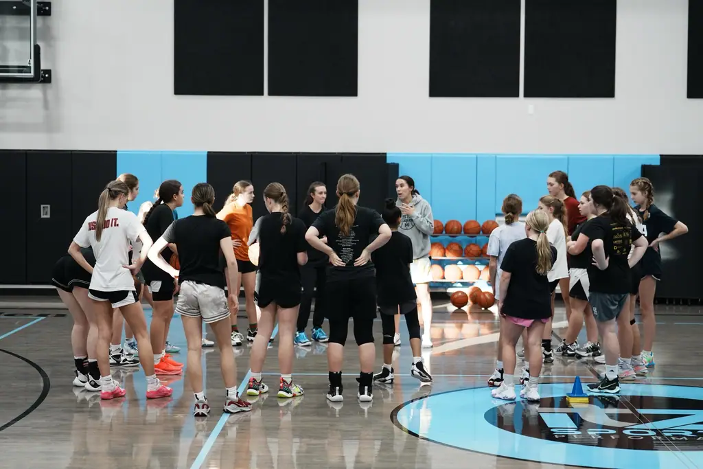 A team gathered around a coach at mid-court